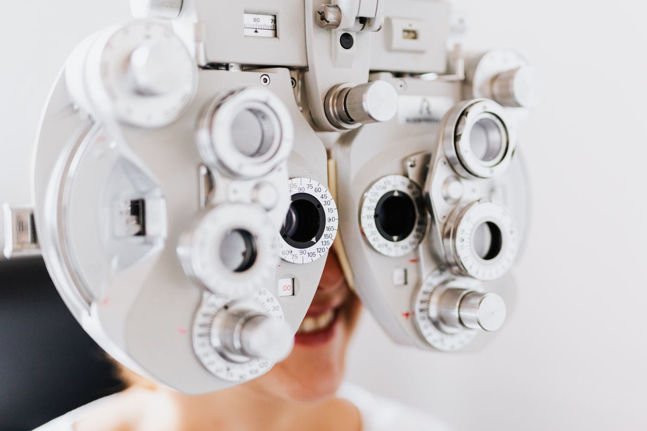 Close-up of woman undergoing an eye examination using a phoropter to test vision.